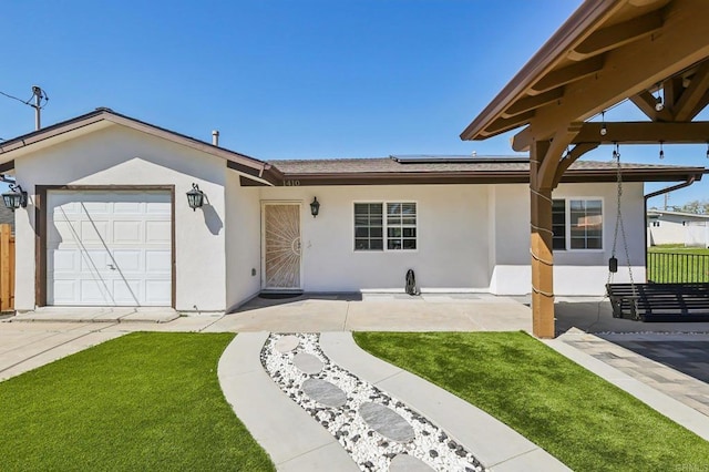 ranch-style house featuring stucco siding, roof mounted solar panels, a garage, and fence