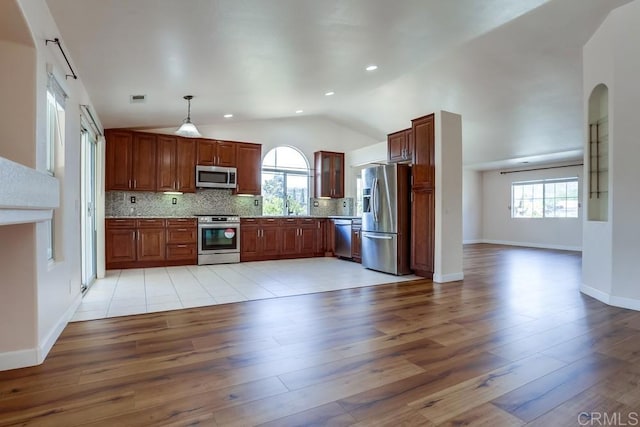 kitchen featuring visible vents, a sink, backsplash, appliances with stainless steel finishes, and light wood finished floors