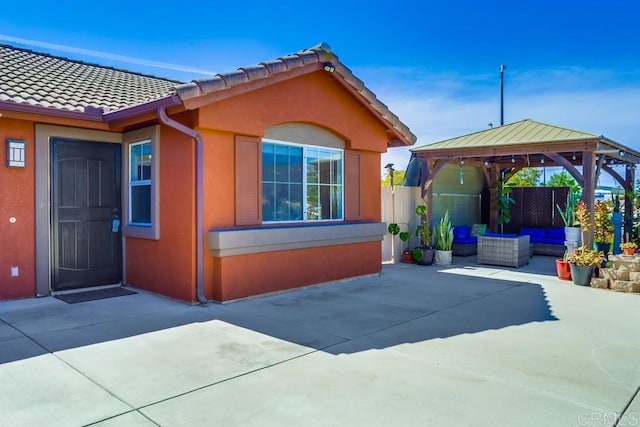 view of property exterior featuring a gazebo, stucco siding, a patio, and fence