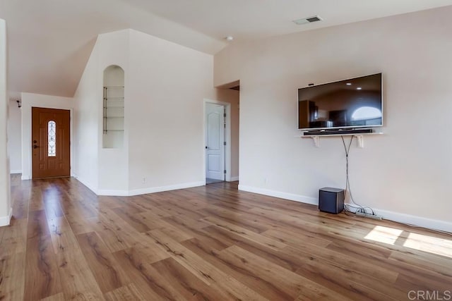 unfurnished living room featuring vaulted ceiling, wood finished floors, visible vents, and baseboards