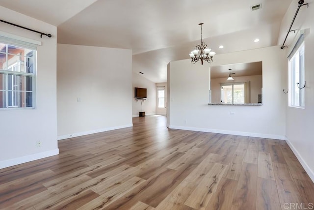 unfurnished living room featuring lofted ceiling, wood finished floors, recessed lighting, baseboards, and a chandelier