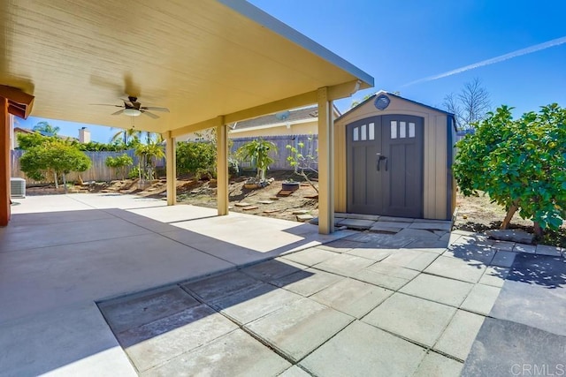 view of patio / terrace featuring an outbuilding, a storage unit, a fenced backyard, and a ceiling fan