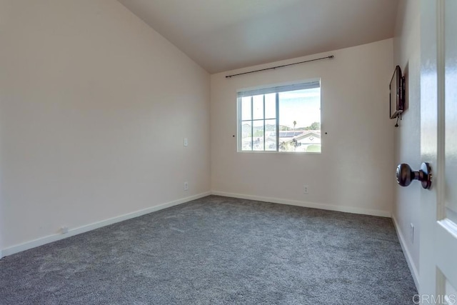 carpeted empty room with baseboards and vaulted ceiling