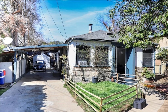 view of front of property featuring stone siding, a carport, roof with shingles, and driveway