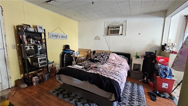 bedroom with an AC wall unit and wood finished floors