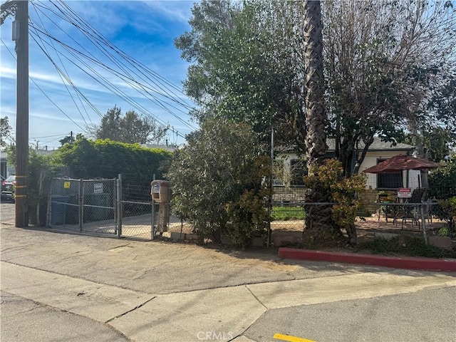 view of property hidden behind natural elements featuring fence and a gate