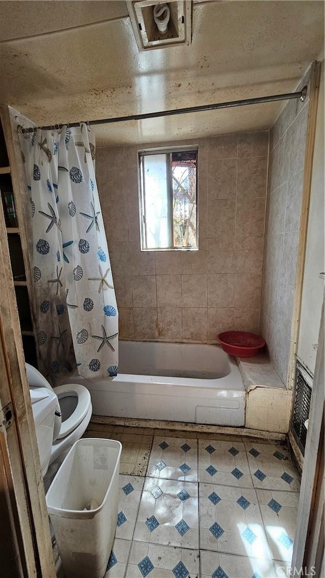 bathroom featuring shower / bath combo with shower curtain, toilet, and tile patterned flooring