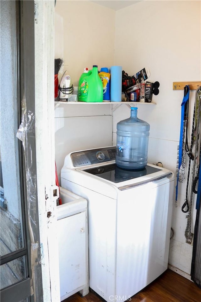 laundry area featuring wainscoting, laundry area, washing machine and dryer, and wood finished floors