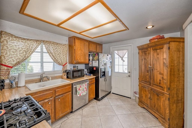 kitchen featuring a sink, appliances with stainless steel finishes, brown cabinetry, and light countertops