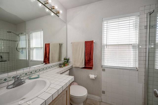 bathroom with toilet, a tile shower, decorative backsplash, baseboards, and vanity