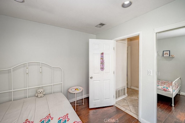 bedroom with visible vents, baseboards, and wood finished floors