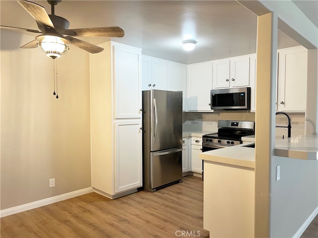 kitchen with a sink, decorative backsplash, stainless steel appliances, white cabinets, and light wood-type flooring