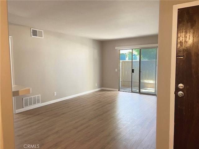 unfurnished room featuring visible vents, baseboards, and wood finished floors