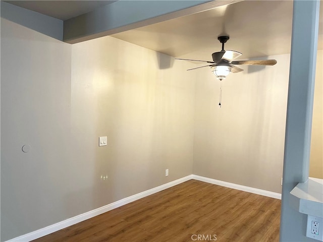 empty room featuring a ceiling fan, baseboards, and wood finished floors