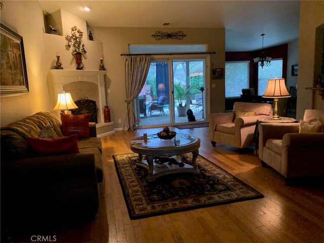 living area featuring a chandelier, a fireplace, and hardwood / wood-style flooring