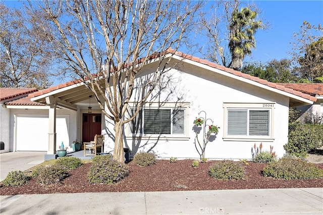 view of front of house with a tile roof, a garage, driveway, and stucco siding