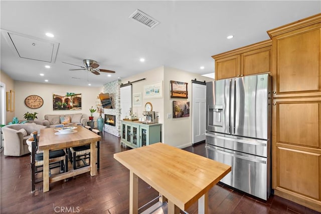 kitchen featuring visible vents, recessed lighting, dark wood-type flooring, stainless steel refrigerator with ice dispenser, and a barn door