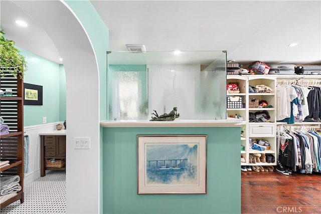 walk in closet featuring arched walkways, visible vents, and wood finished floors