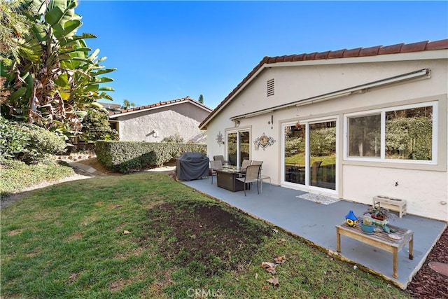 back of property with stucco siding, a lawn, and a patio area