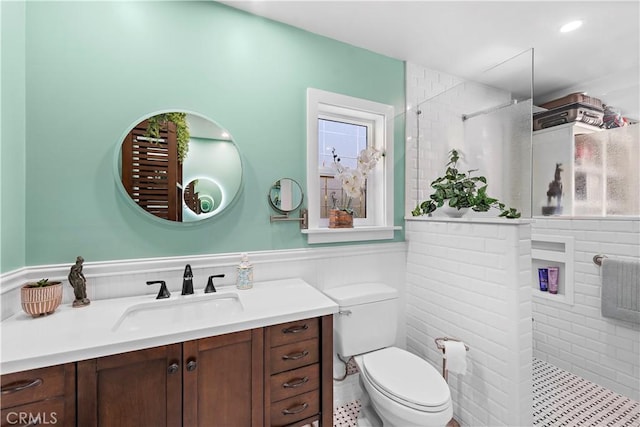 bathroom featuring vanity, toilet, a wainscoted wall, and walk in shower