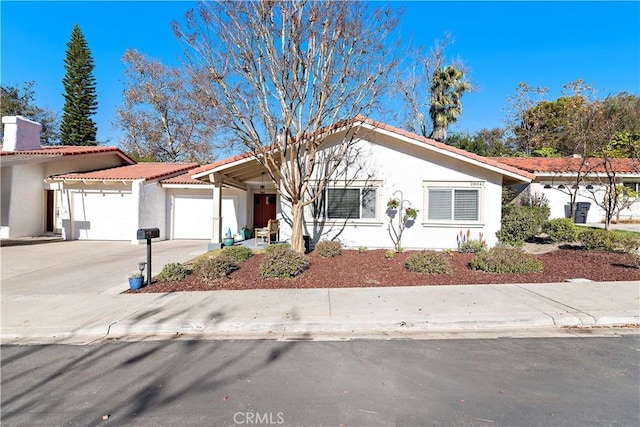 view of front facade featuring a tile roof, stucco siding, an attached garage, and concrete driveway