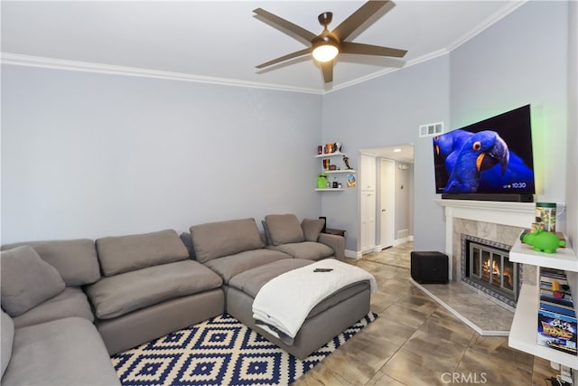 living area with visible vents, ornamental molding, baseboards, ceiling fan, and a tile fireplace