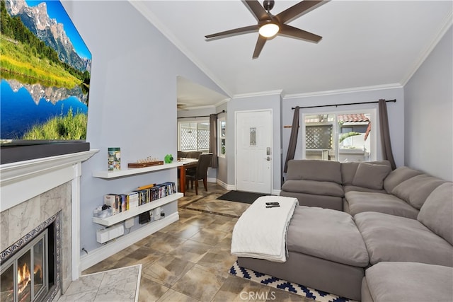 living area featuring baseboards, a premium fireplace, ceiling fan, ornamental molding, and vaulted ceiling