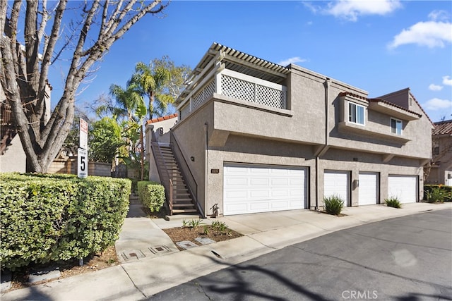 multi unit property with stairway, stucco siding, and a garage