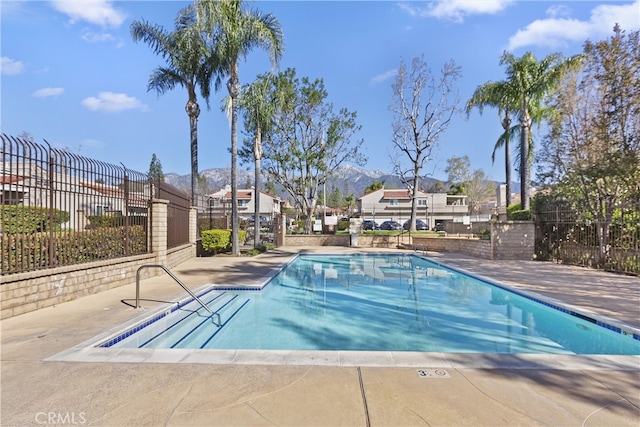 community pool with a residential view, a mountain view, a patio, and fence