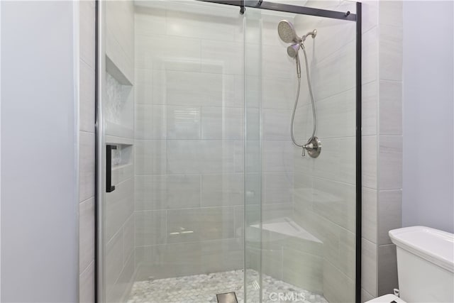 bathroom featuring toilet and a shower stall