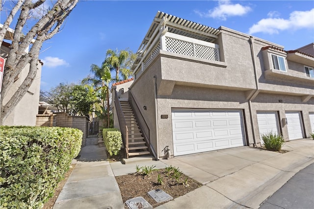 view of front of property with stairs, concrete driveway, a garage, and stucco siding