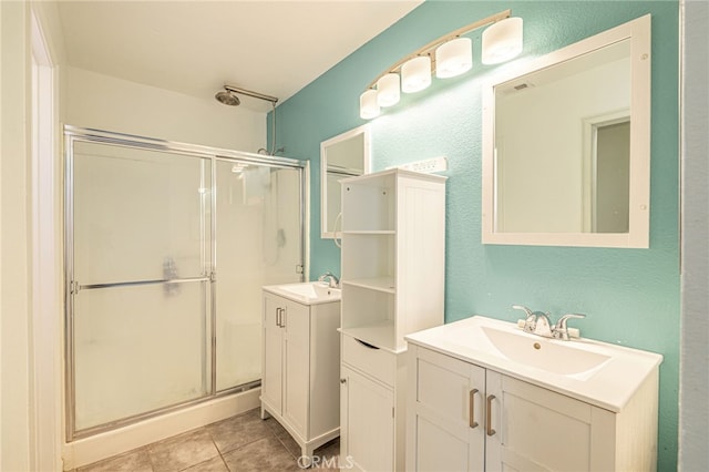 full bath featuring a sink, two vanities, a stall shower, and tile patterned floors