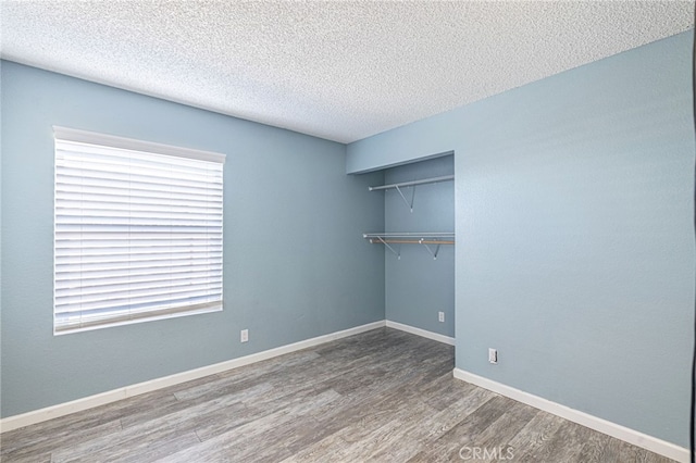 spare room with a textured ceiling, baseboards, and wood finished floors