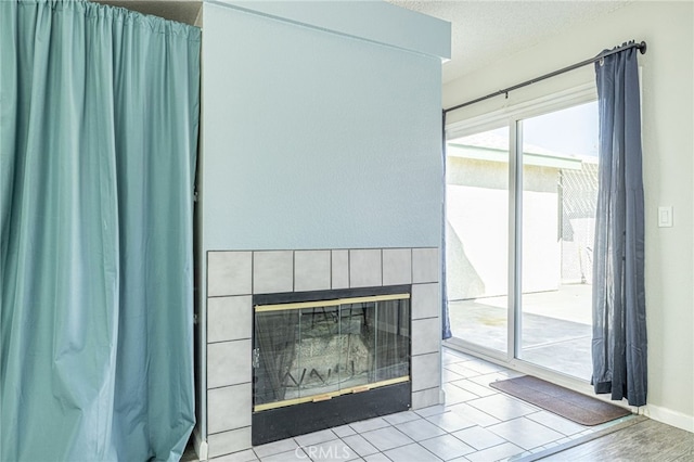 interior details featuring a textured ceiling, wood finished floors, and a tile fireplace