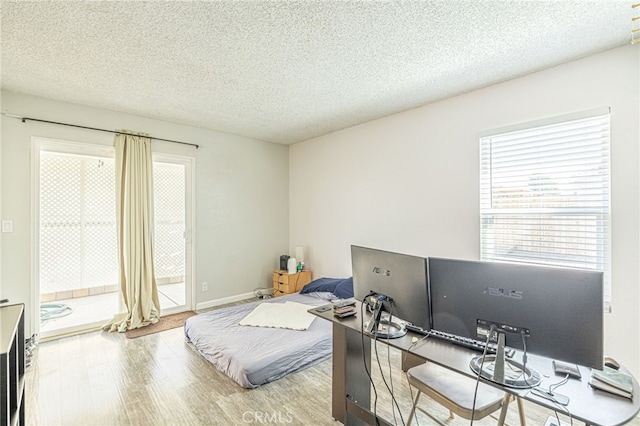 bedroom featuring a textured ceiling, wood finished floors, and access to exterior