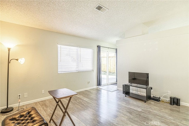 interior space featuring visible vents, a textured ceiling, baseboards, and wood finished floors