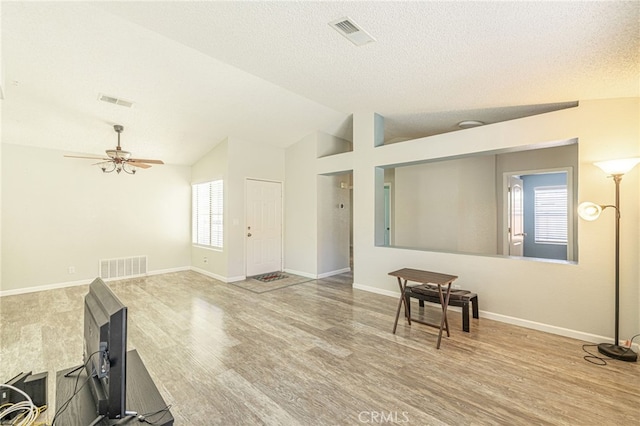 living room with visible vents, lofted ceiling, plenty of natural light, and wood finished floors