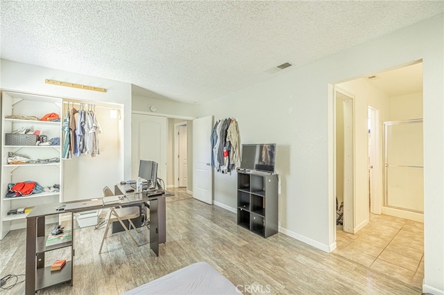 office space featuring visible vents, baseboards, a textured ceiling, and wood finished floors