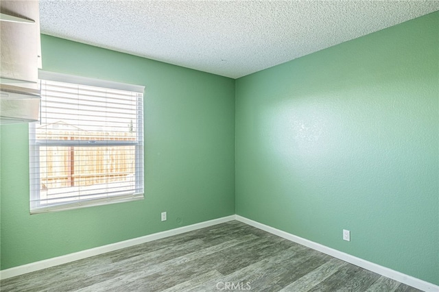 empty room featuring baseboards, a textured ceiling, and wood finished floors