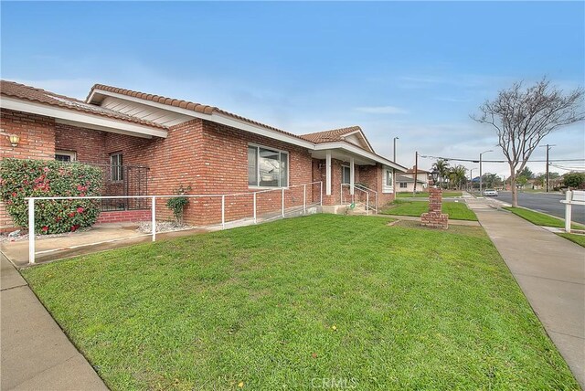 12460 Magnolia Ave, Chino, CA 91710 - view of home's exterior featuring a yard, a tile roof, and brick siding