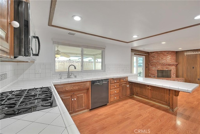 12460 Magnolia Ave, Chino, CA 91710 - kitchen featuring a sink, brown cabinets, a peninsula, black appliances, and a fireplace