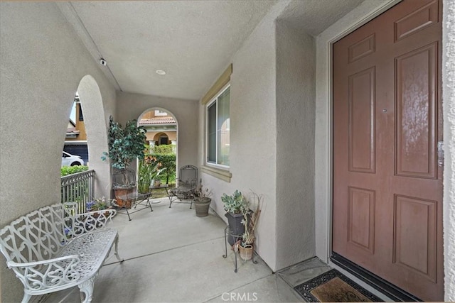 doorway to property featuring stucco siding and a porch