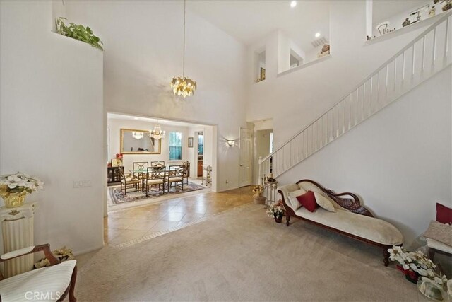 carpeted entrance foyer with tile patterned flooring, a notable chandelier, stairway, and a high ceiling