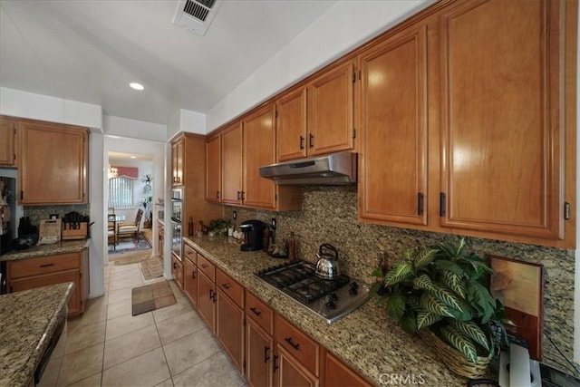 kitchen with under cabinet range hood, visible vents, brown cabinets, and stainless steel gas stovetop