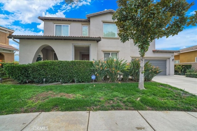 mediterranean / spanish house with a front lawn, a tiled roof, concrete driveway, stucco siding, and an attached garage