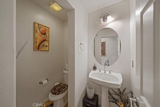 bathroom featuring a sink, baseboards, and toilet