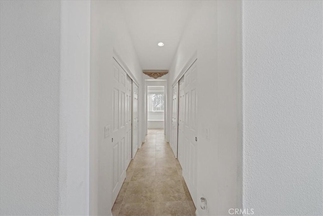 hallway with light tile patterned flooring and a textured wall