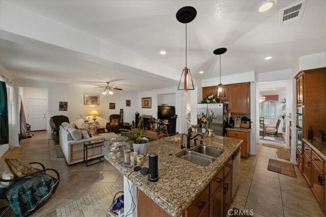 kitchen featuring visible vents, a sink, open floor plan, appliances with stainless steel finishes, and brown cabinets