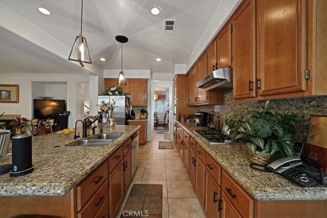 kitchen featuring visible vents, under cabinet range hood, a sink, stainless steel appliances, and brown cabinetry