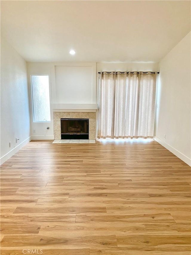 unfurnished living room with baseboards, light wood-style flooring, and a fireplace